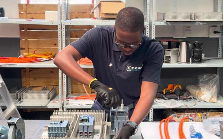 A PLC Masters engineer wiring a control panel backplate